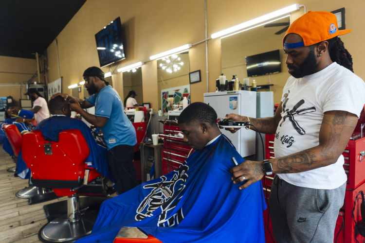 Left to right: Upscale Kutz Barber Shop barbers Dennis Ross, Karlos Burt and Trell Turner cut the hair of Bernard, Riko, and Jaytin. (Ziggy Mack)  