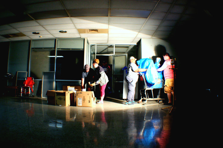 Volunteers work by task lighting in the darkened Coliseum corridors. Volunteers found a number of interesting items including decorative plastic trees, a toaster oven, a disassembled tricycle, a Santa suit and a single baby shoe. (Shelda Edwards) 