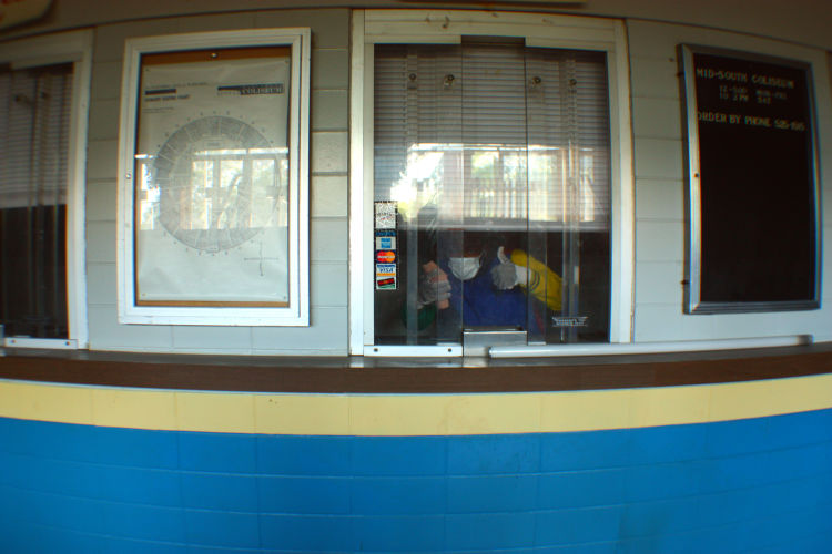 A volunteer in a protective mask gives a thumbs-up from inside the Coliseum's will call office. (Shelda Edwards).Â   