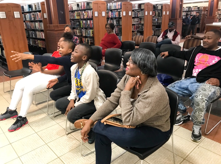 Young viewers react with excitement after a play in the first quarter. Carrie Mitchell sits in the foreground on the front row and behind her sits Antonio Pickens. (Cole Bradley)