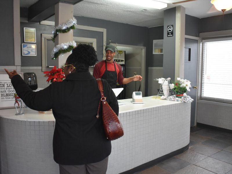 A customer points to the menu with a question and Tavias Ford answers with a smile at Vivian's Down Home Cooking in Binghampton. (Taylor Moore)