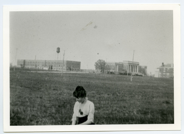 Circa 1915, a student of the West Tennessee Normal School sits in a field located roughly at present-day Walker Avenue between Brister and Patterson streets. The distant building with columns is the university's present-day administration building. (Special Collections, University of Memphis Libraries)