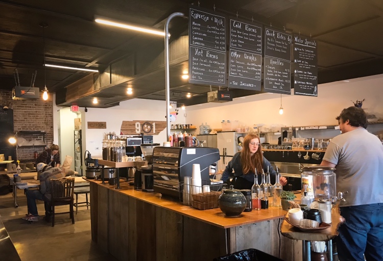 Barista Annie Harmon serves a customer on the coffee side of Belltown Artisans while makers work in the ceramics area behind her. (Cole Bradley)