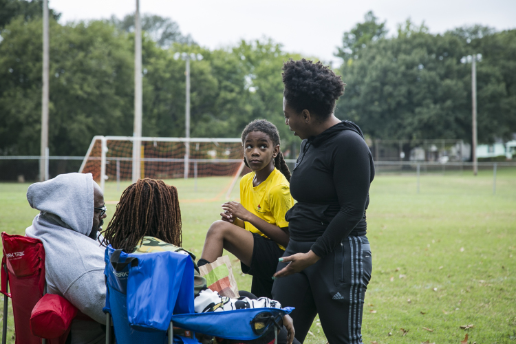 Coach Tori Jones, 27, of Pyramid Athletics speaks to the Vaughn Family at half time of a soccer game at Gaisman Park. (Natalie Eddings)