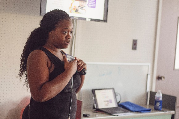 Starlett Douglas shows caregivers how to position a recording device on their child. The devices monitor how many conversations the child is engaged in and how many electronic devices are nearby. (Agape)