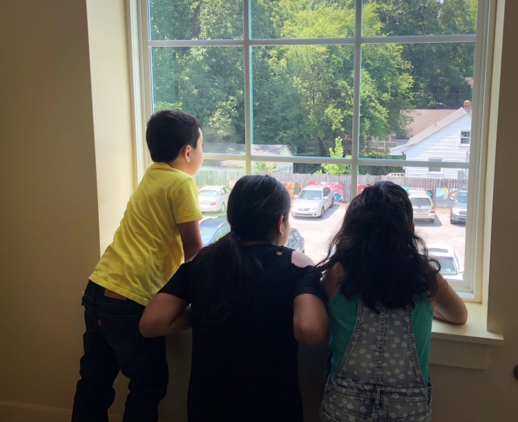 Neighborhood children look down Harvard Avenue from one of Caritas' new energy efficient windows. (Shelda Edwards)