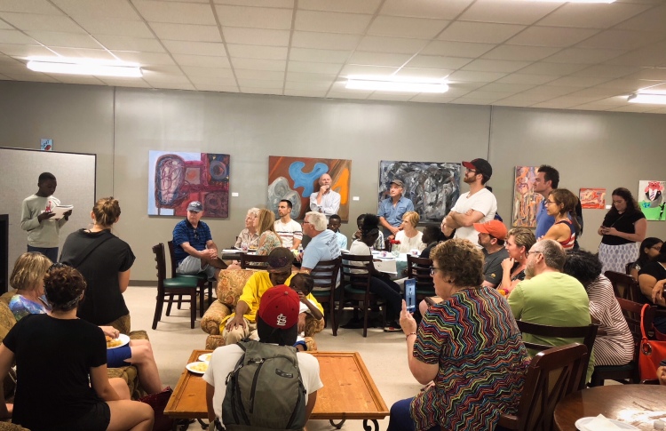 At the reopening, neighbors took a moment to listen to a young boy tell a story he workshopped with Caritas board member, Blake Barber. (Shelda Edwards)