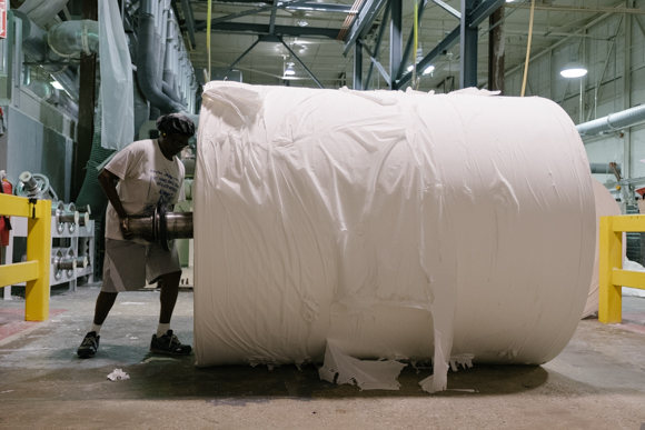 A woman prepares a parent roll to be lifted into a machine. (Brandon Dahlberg)