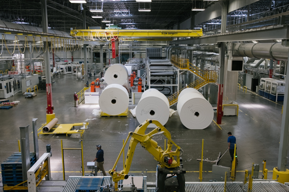 A man sweeps the factory floor in front of parent rolls waiting to be loaded into a machine. (Brandon Dahlberg)
